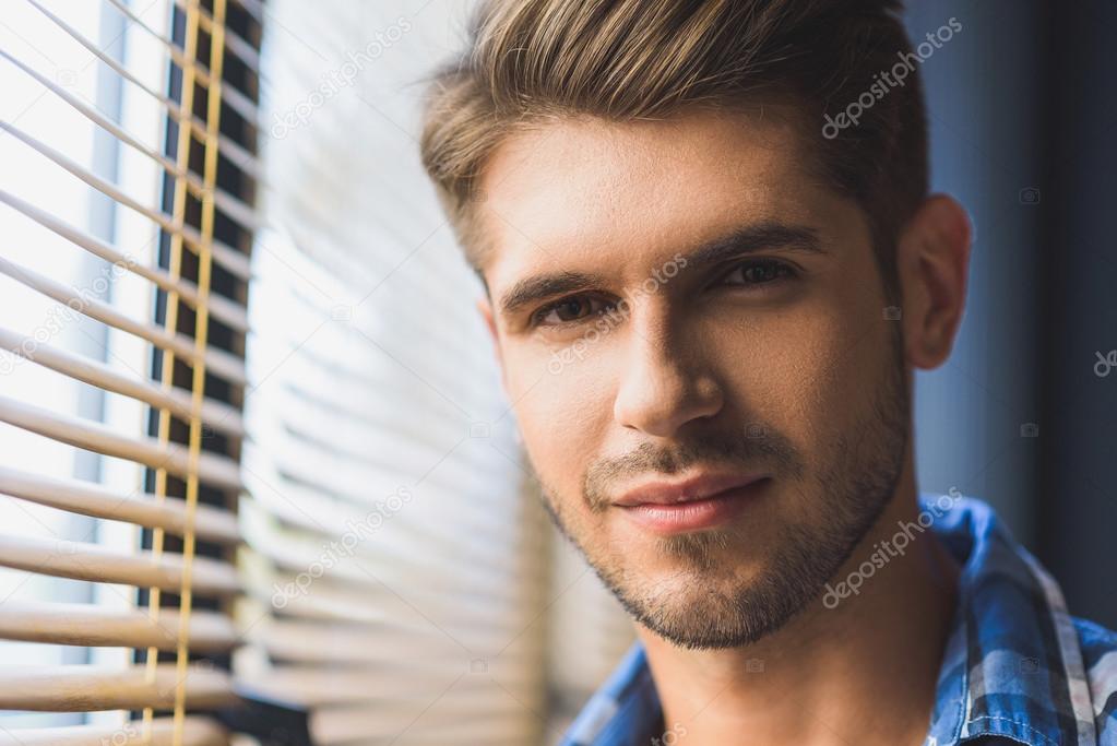 good looking man in front of a window