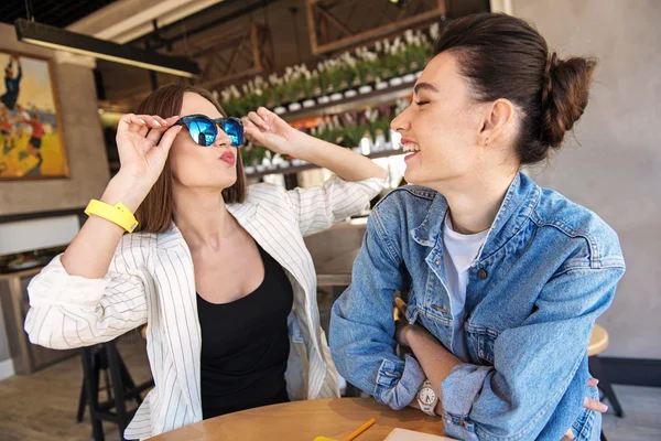 Молодая женщина примеряет солнцезащитные очки перед своей подругой — стоковое фото