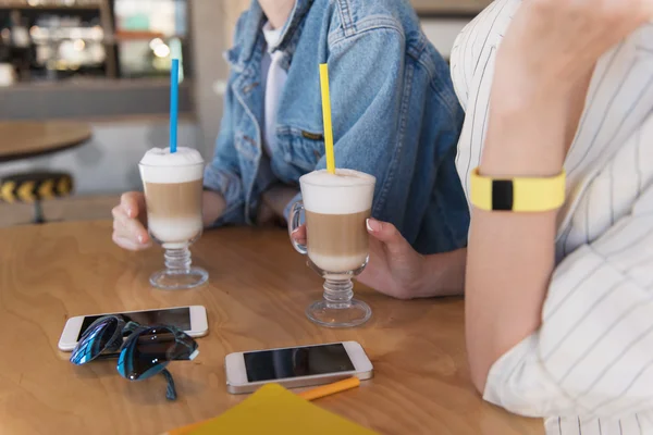 Närbild av en telefoner på ett bord medan flickor håller sina drinkar — Stockfoto