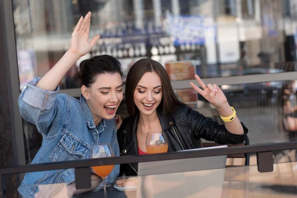 Chicas felices hablando con alguien en una videollamada desde el portátil —  Fotos de Stock