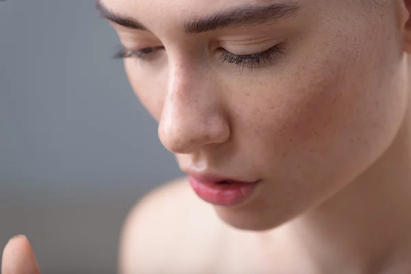 Cara de chica con pecas sobre fondo gris y espacio de copia — Foto de Stock