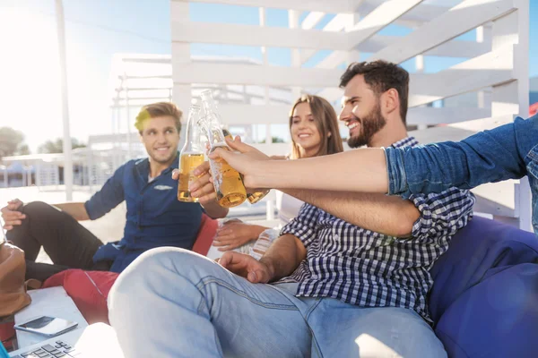 Colleagues clinking bottles on the beach — Stock Photo, Image