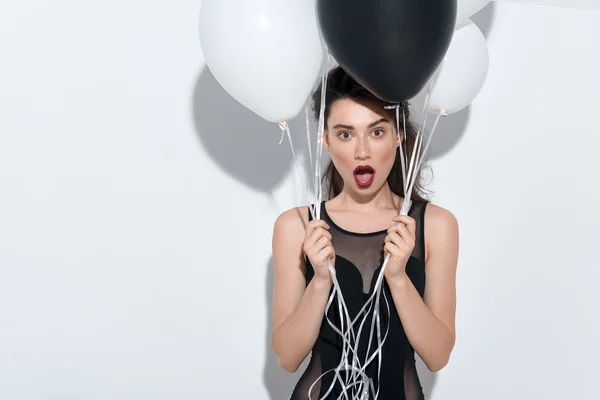 Waist up of a shocked girl holding balloons — Stock Photo, Image