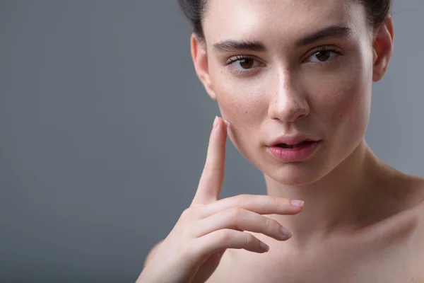 奶油在她的手，脸上有雀斑的女人灰色背景 — 图库照片