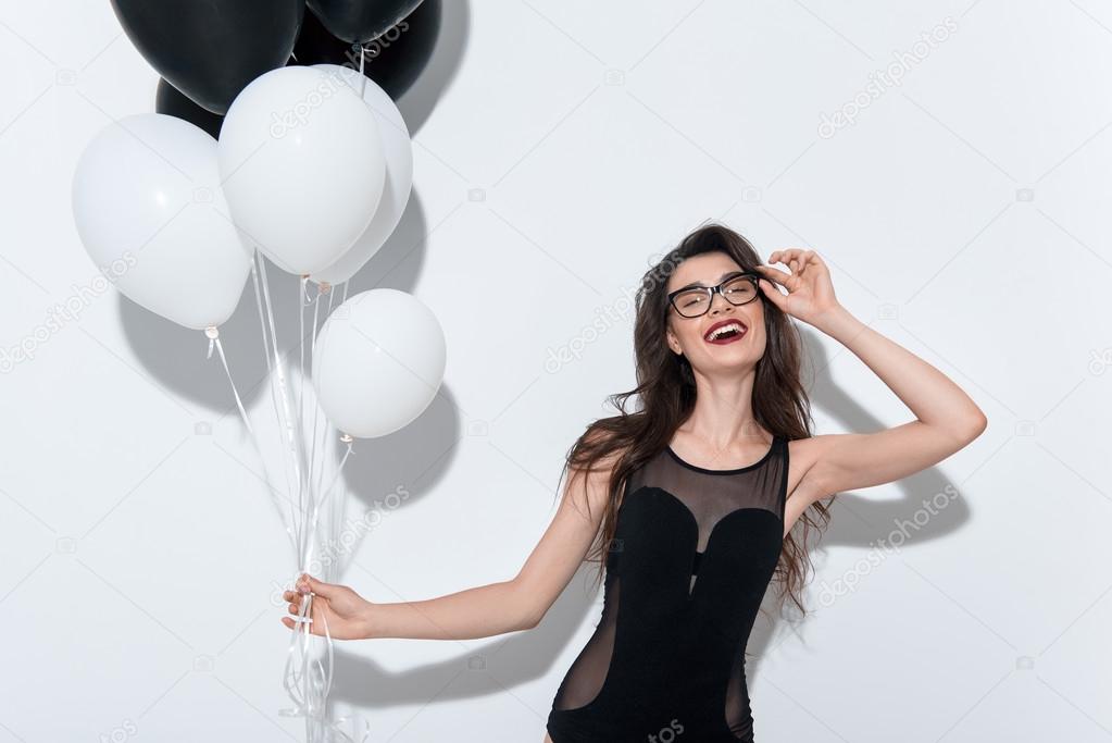 waist up of a young happy model holding balloons