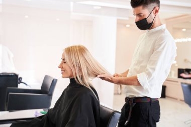 Adam müşterisinin uzun sarı saçlarına bakıyor.