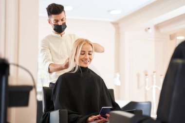 Gülümseyen ve akıllı telefona bakan bir bayan.