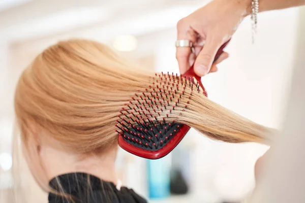 Cabeleireiro escovação longo cabelo loiro — Fotografia de Stock