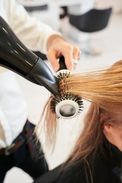 Frisör torkar kvinnligt hår med hårtork — Stockfoto