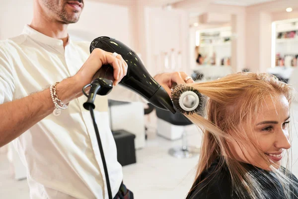 Cabeleireiro usando ventilador e escova para secar o cabelo — Fotografia de Stock