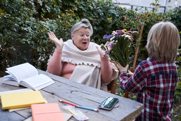 Grandmother accepting wildflowers from kid — Stock Photo, Image