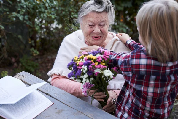 Criança trazendo buquê de flores para sua avó favorita — Fotografia de Stock