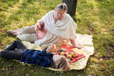 Büyükanne piknikte torunuyla konuşuyor.