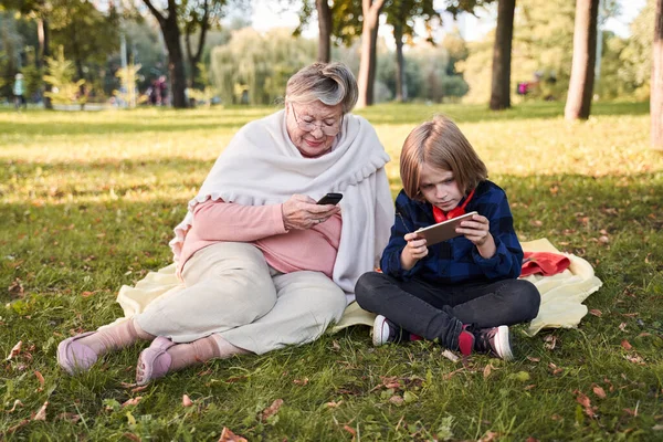 Mormor och barn tittar på sina telefoner — Stockfoto