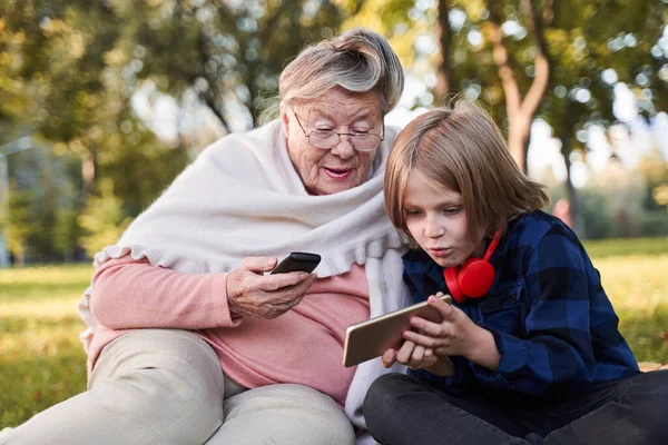 Хлопчик показує щось своїй бабусі на свій смартфон — стокове фото