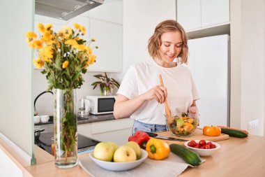 Tahta kaşıkla sebze karıştıran bir kadın.