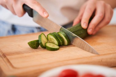 Bir kadın bıçakla salatalık doğruyor.