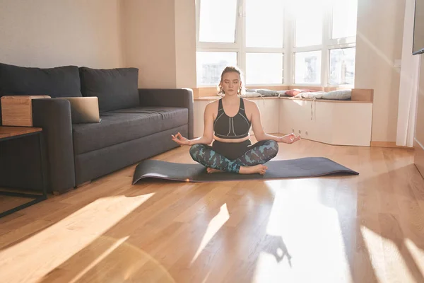 Žena medituje ve svém útulném obývacím pokoji — Stock fotografie