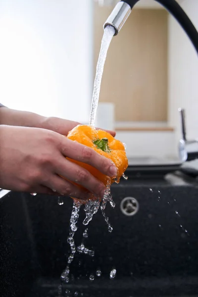 Woman washing vegetables in domestic kitchen