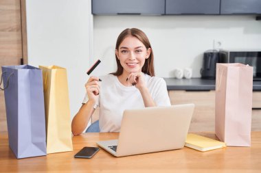 Kredi kartı tutan ve gülümseyen bir kadın.