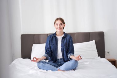 Kadın rahat yatak odasında meditasyon yapıyor.