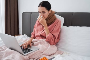 Hasta kadın yatak odasında dizüstü bilgisayar kullanıyor.