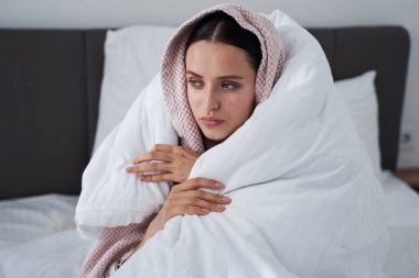 İki battaniyenin altında oturan kız.