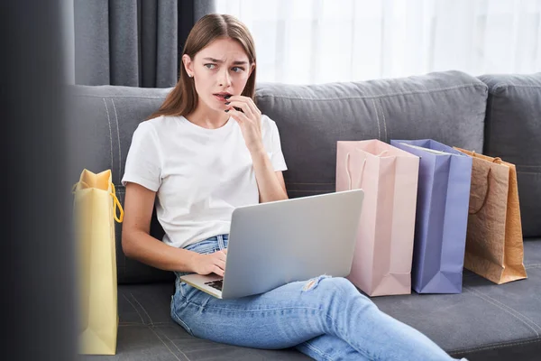 Kvinna förbryllad när du sitter i soffan — Stockfoto