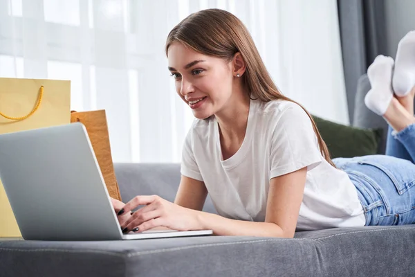 Flicka ligger på den grå mysiga soffan — Stockfoto