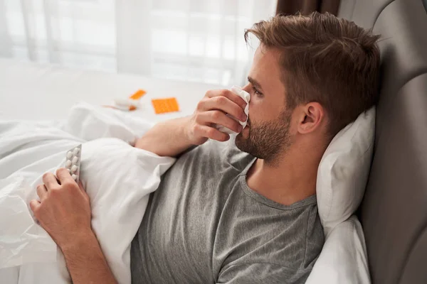 Hombre acostado en la cama cubierto con manta — Foto de Stock