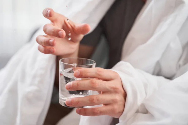 Un homme jetant une pilule dans un verre d'eau — Photo