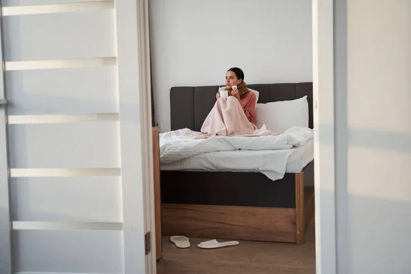 Vrouw die het koud heeft terwijl ze op bed zit — Stockfoto