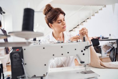 Kadın terzi oturuyor ve dikiş dikiyor.