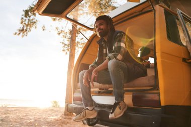 Arabanın bagajında oturan adam.