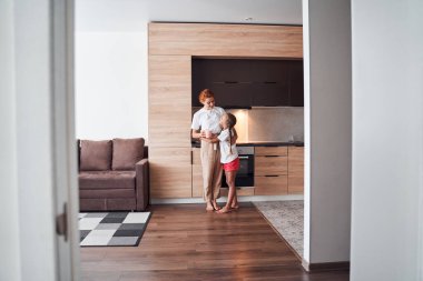 Anne kızına sarılıyor.