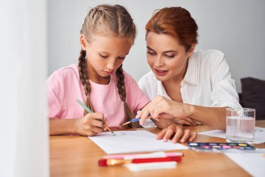 Anne çocuğuyla resim çiziyor.