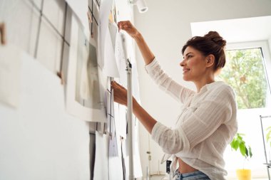 Kadın bitmiş çizimlerine bakıyor.