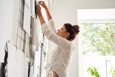 Tamamlanmış taslağı duvara iliştiren kadın