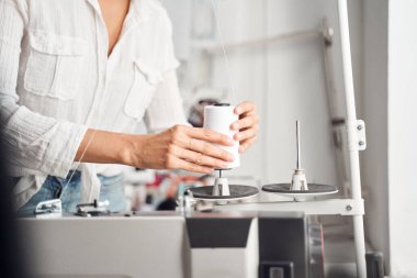 Tasarımcı bir makara beyaz iplik takıyor