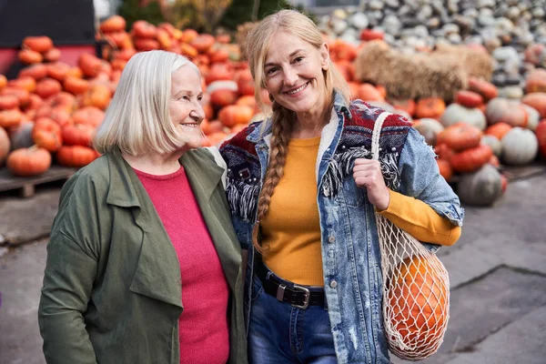 Mujer de pie en el mercado de otoño y mirando a su hija —  Fotos de Stock