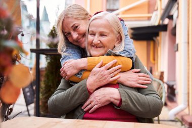 Kadın ve yaşlı annesi şehir caddesinde kucaklaşıyorlar.