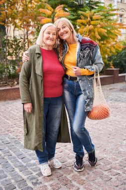 Anne ve kızı kameraya gülümsüyor.