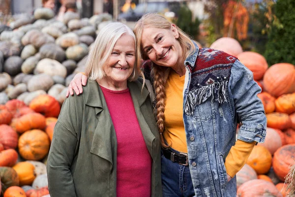 Woman standing at the autumn market with her blonde adult daughter — Stock Photo, Image