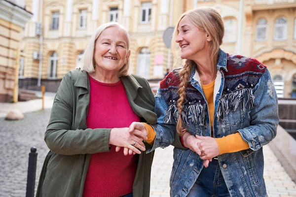 Woman walking arm in arm with her dear senior mother — Stock Photo, Image