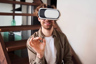 Adam merdivenlerde otururken sanal gerçeklik deneyimi yaşıyor.