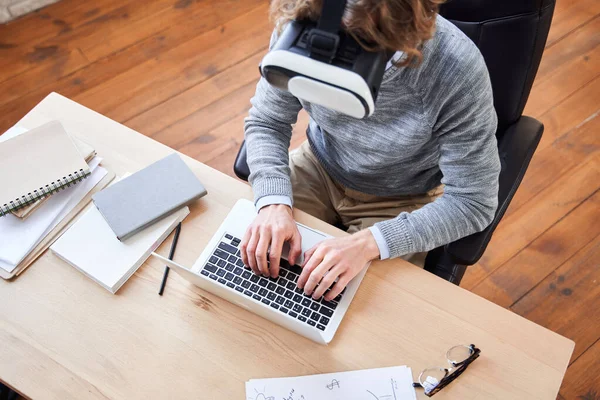 Man sitting at the desk and typing something at the laptop keyboard — Stock Photo, Image