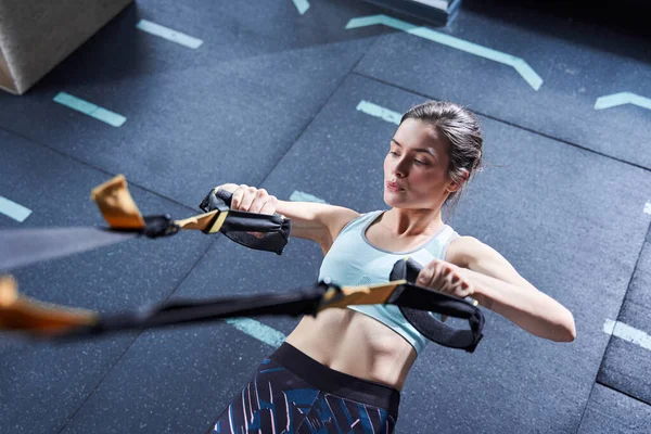 Mujer usando correas trx mientras entrena cuerpo más fuerte — Foto de Stock