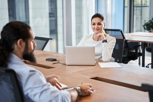 Businesswoman is smiling while sitting at the table