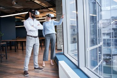 Meslektaşının yanında duran bir kadın işaret ediyor.