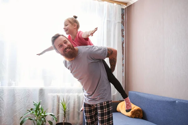 Chica volando sobre su apuesto padre barbudo — Foto de Stock